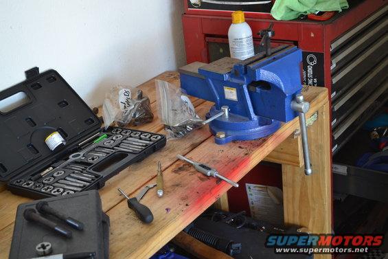 Workbench with blue vise, tap and die set, and assorted hardware
