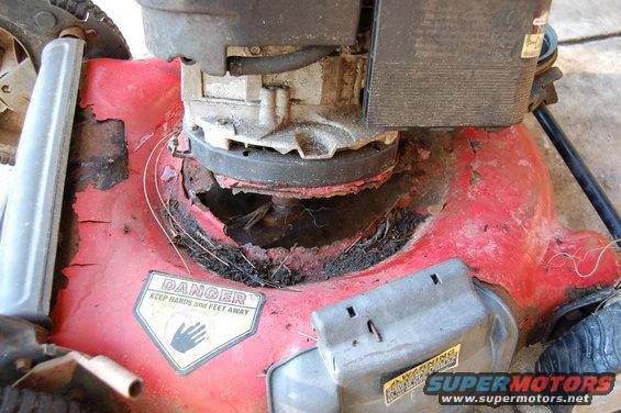 Red lawn mower deck showing significant rust and damage around the blade housing. Includes a DANGER sticker