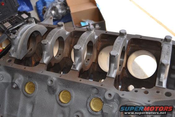 Engine block with crankshaft bearing caps installed. Some brass plugs are visible on the side