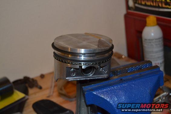 Engine piston held in a blue vise on a workbench