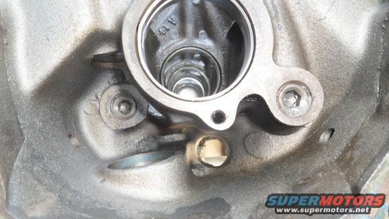 Close-up of a metal engine component with internal cylindrical features and bolt holes