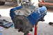 1981 Ford F-250 - Engine assembly with blue valve covers and chrome carburetor, tools and another vehicle visible in the background.