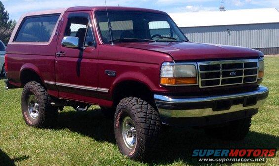 Red 1996 Ford Bronco with tan top and lifted suspension
