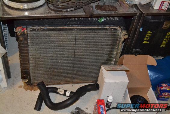 Radiator and hoses on a concrete floor with boxes and air filter in the background