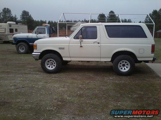 1990 Ford Bronco parked next to a blue Ford pickup truck