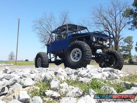 Blue off-road buggy with roll cage and large tires on rocky terrain