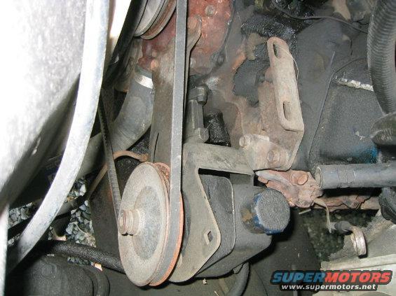 Engine belt and pulley system with rust and grime. A blue cap is visible