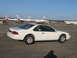 1995 Ford Thunderbird - Side view of a white 1995 Ford Thunderbird coupe parked on an asphalt lot with airplanes in the background.