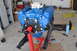 1981 Ford F-250 - A blue V8 engine is mounted on a red engine stand, with tools and supplies scattered around the garage floor.