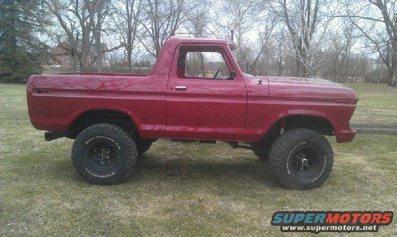 side view of red pickup truck with lifted suspension and off-road tires
