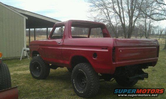 Red 1978 Ford Bronco with lifted suspension and off-road tires, viewed from the rear three-quarter angle