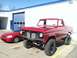 1978 Ford Bronco - Red 1977 Ford F-150 pickup truck and a red sedan parked outside a building.