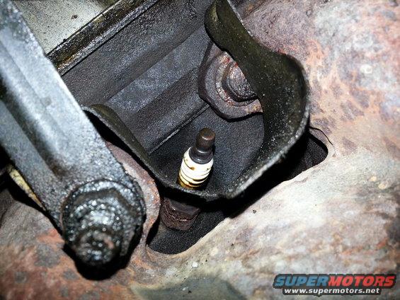 Spark plug installed in an engine block, surrounded by greasy metal components