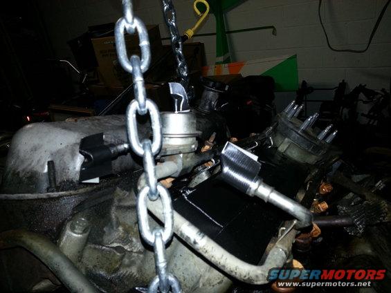 Engine block with chains attached, showing distributor cap and spark plug wires