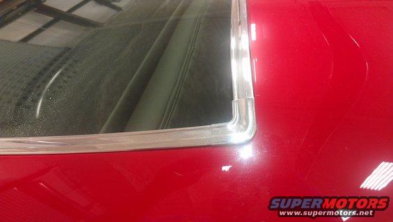 Red car rear window trim and interior detail. Watermark "SUPERMOTORS www.supermotors.net"
