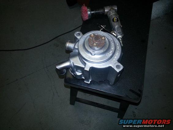Silver water pump with attached air tool and wire brush on a black stool