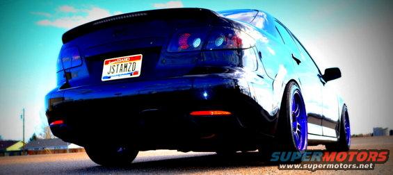 Dark blue sedan from rear, with custom blue wheels and a spoiler