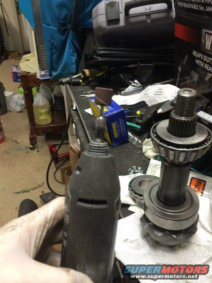 Dremel tool held over differential gears and bearings on a workbench