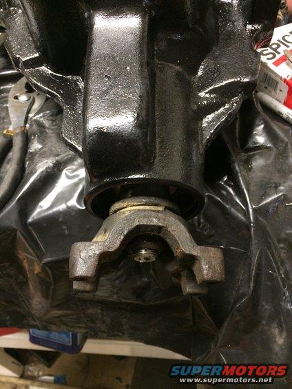 Close-up of a differential housing with a driveshaft yoke attached. A wrench is visible in the background