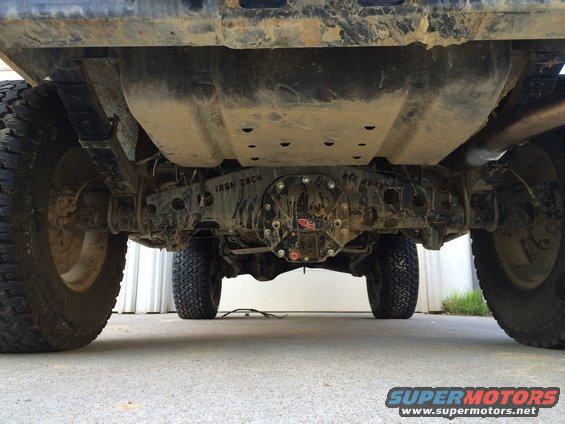 Underside view of a truck's rear axle with 'IRON ROCK' visible on the differential cover