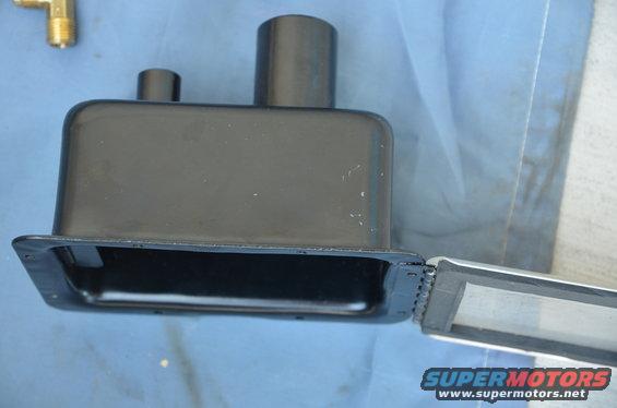 Black metal part with two cylindrical protrusions and a hinged lid