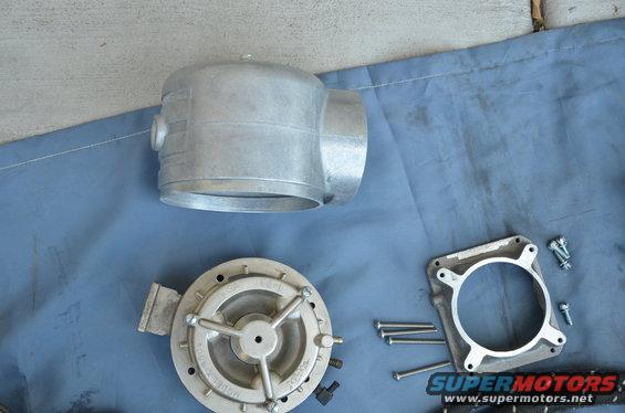 Aluminum carburetor body, diaphragm, and mounting plate with screws on a blue cloth