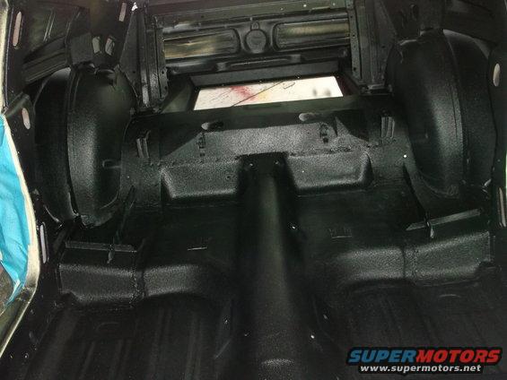 Car trunk interior with black textured coating on floor and wheel wells