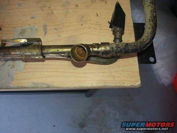 metal pipe assembly with a black flap on a wooden surface