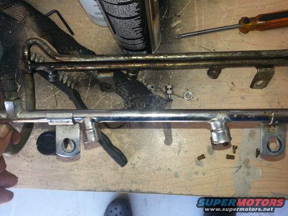 Fuel rail with injectors removed, on a workbench with tools