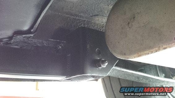 Underside of a vehicle showing a bracket and exhaust pipe. Text 'SUPERMOTORS.NET' is visible