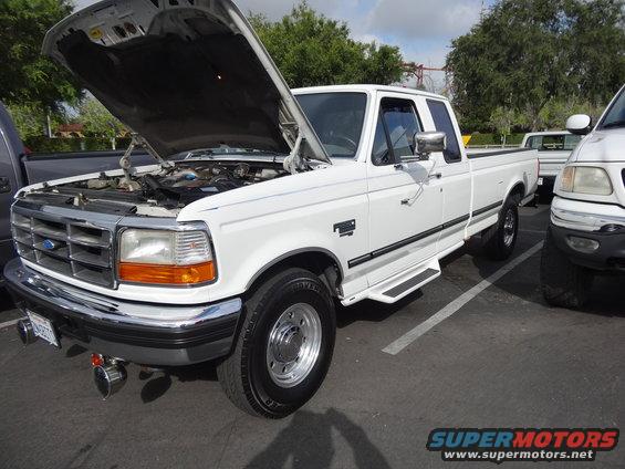 White Ford F-250 pickup truck with hood open, parked next to another truck