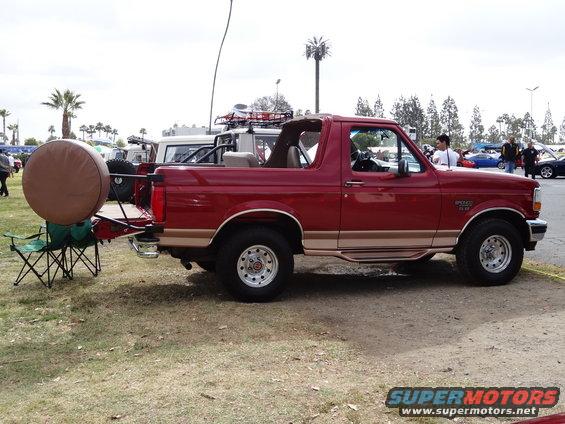 Red 1994 Ford Bronco with tan trim, spare tire on rear carrier, and roof rack