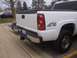 2006 Chevrolet Silverado 2500 - The rear of a white Chevrolet Silverado pickup truck is shown, a chrome bumper and a 4x4 decal on the fender.