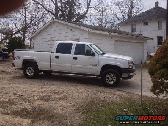 White 2006 Chevrolet Silverado 2500 pickup truck parked in front of a garage