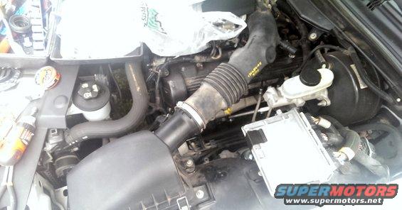Engine bay with air intake tube, brake booster, and computer module visible
