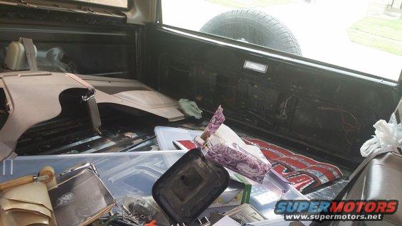 Interior of a 1994 Ford Bronco cargo area filled with parts and storage bins. Spare tire visible