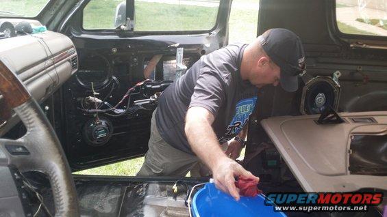 Interior view of a vehicle with door panel removed, man cleaning