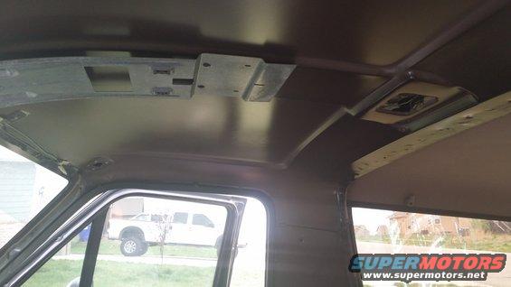 Interior view of a vehicle, looking towards the ceiling. A white pickup truck is visible through the side window