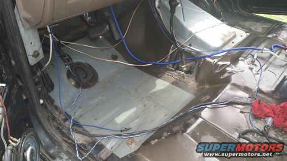 Interior floor of a vehicle with exposed wiring and some rust