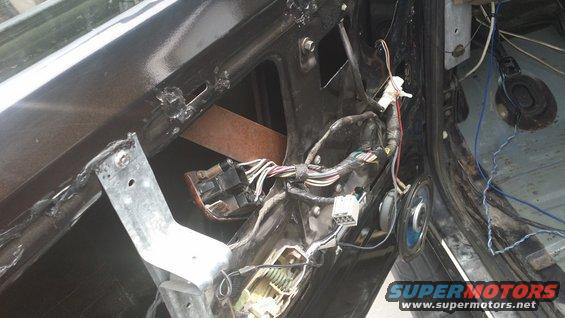 Car door interior with exposed wiring, speaker, and metal bracket