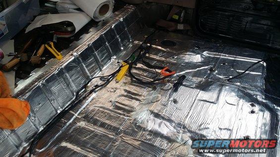Vehicle floor covered in soundproofing material with wiring visible