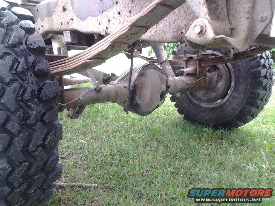 Rear axle assembly with leaf springs and tire visible on a truck