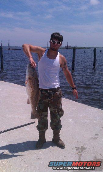 Man holding a large red drum fish on a pier