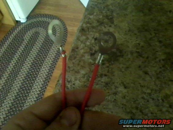 Two red wires with metal ring terminals held in a hand