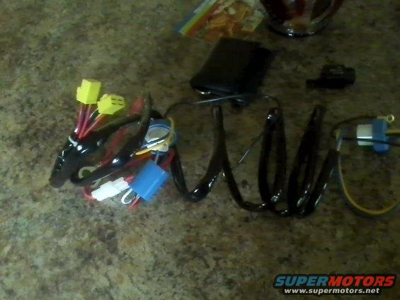 Wiring harness with yellow and white connectors, blue and black components, and coiled black tubing on a speckled countertop