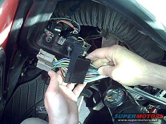 Hands manipulating a vehicle's dashboard wiring harness and ignition switch assembly