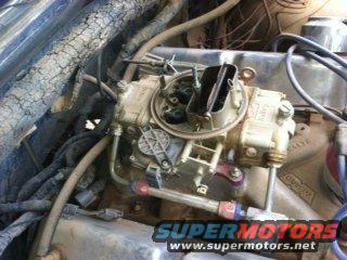 Engine carburetor with visible fuel lines and wiring. Text overlay reads SUPERMOTORS