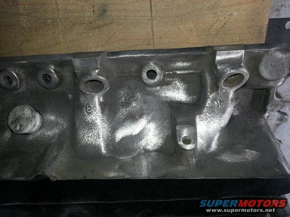 Close-up of a cast metal engine block with bolt holes and casting marks