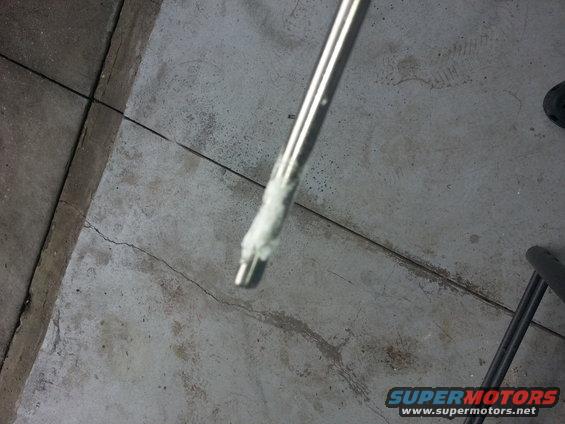 Metal rod with white paste on its end, resting on a concrete floor