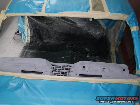 Dashboard part covered in primer, taped off for painting